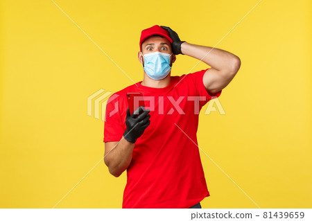 Food delivery, tracking orders, covid-19 and self-quarantine concept. Worried and nervous courier in red uniform and medical mask, touch head anxious, holding smartphone, read intimidating news 81439659