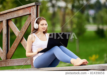 Woman talks with friends using laptop and Internet outdoors. Woman talks with friends using laptop and Internet outdoors. 81439858