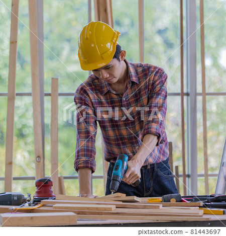young asian handsome male wearing orange hard safty helmet lean over working table full of equipments smiling inside industrial working site young asian handsome male wearing orange hard safty helmet lean over working table full of equipments smiling inside industrial working site 81443697