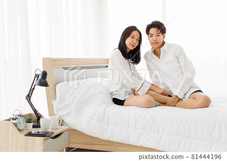 LGBTQ couple lovers, a handsome girl as man or butch and femme, spending and sharing loving time in white bedroom with fun, warmth, and happiness 81444196