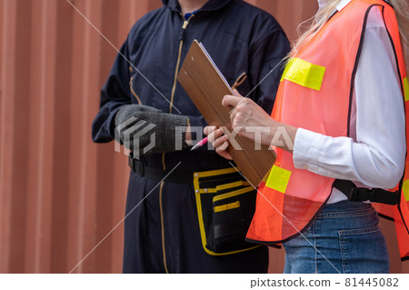 Industrial worker works with co-worker at overseas shipping container yard 81445082
