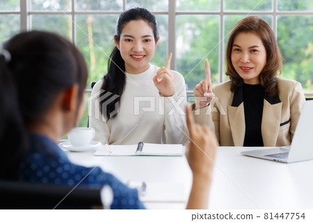 Deaf translator teaching two businesswomen to use and understand hand language sign 81447754