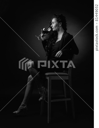Portrait of attractive brunette with glass of wine on a black bacground. Portrait of attractive brunette with glass of wine on a black bacground. 81449032