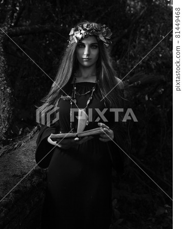 Beautiful young halloween witch wearing vintage gothic dress and holding magical book. 81449468