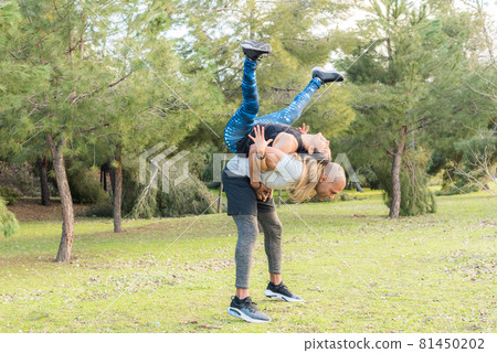 Fitness couple doing back to back lifting exercise in the park 81450202
