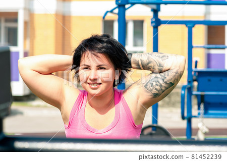 young woman shakes her back muscles in the city yard using street exercise machine hyper extension bench young woman shakes her back muscles in the city yard using street exercise machine hyper extension bench 81452239