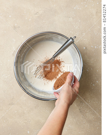 cocoa powder is added to the whipped eggs and sugar in a metal bowl cocoa powder is added to the whipped eggs and sugar in a metal bowl 81452274