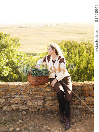 Woman with cabbage sitting on brick fence Woman with cabbage sitting on brick fence 81458942