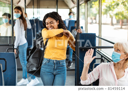 Black woman sneezing and coughing in elbow standing in bus 81459114