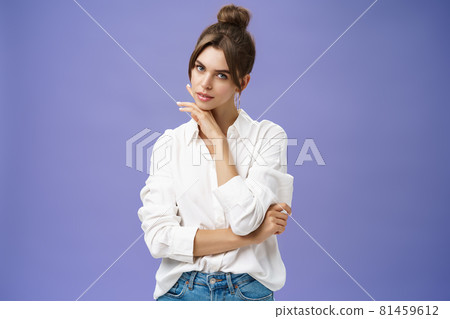 Portrait of tender and feminine stylish woman in white blouse posing sensually and flirty touching chin gazing daring at camera posing against purple background with self-assured expression Portrait of tender and feminine stylish woman in white blouse posing sensually and flirty touching chin gazing daring at camera posing against purple background with self-assured expression 81459612