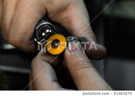 Hands of the jeweler polishes ring on the polishing machine. Goldsmith working on his workbench 81463074