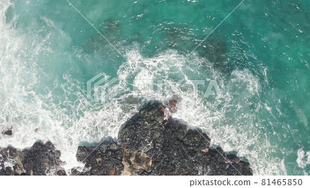Aerial shot from drone. Top view on the rocky ocean shore. Blue Waves of the Pacific Ocean is crashing on the rock. White sea foam. Volcanic beach of Tropical Island Oahu Hawaii. 81465850