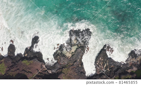 Aerial shot from drone. Top view on the rocky ocean shore. Blue Waves of the Pacific Ocean is crashing on the rock. White sea foam. Volcanic beach of Tropical Island Oahu Hawaii. 81465855