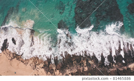 Aerial shot from drone. Top view on the rocky ocean shore. Blue Waves of the Pacific Ocean is crashing on the rock. White sea foam. Volcanic beach of Tropical Island Oahu Hawaii. 81465886