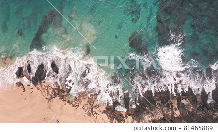 Aerial shot from drone. Top view on the rocky ocean shore. Blue Waves of the Pacific Ocean is crashing on the rock. White sea foam. Volcanic beach of Tropical Island Oahu Hawaii. 81465889