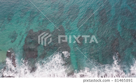 Aerial shot from drone. Top view on the rocky ocean shore. Blue Waves of the Pacific Ocean is crashing on the rock. White sea foam. Volcanic beach of Tropical Island Oahu Hawaii. 81465891