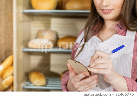 The saleswoman describes the plates for each type of bread. An attractive saleswoman counts the remaining bread for sale. 81466770
