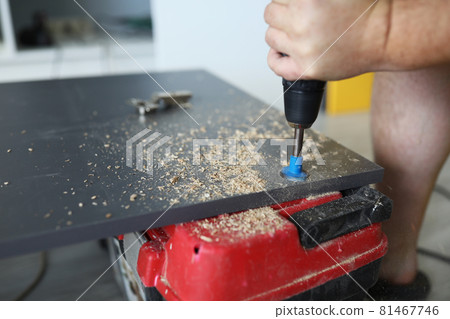 A carpenter makes hole in large piece of furniture 81467746