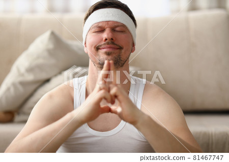 Man meditates while sitting on the floor at home Man meditates while sitting on the floor at home 81467747