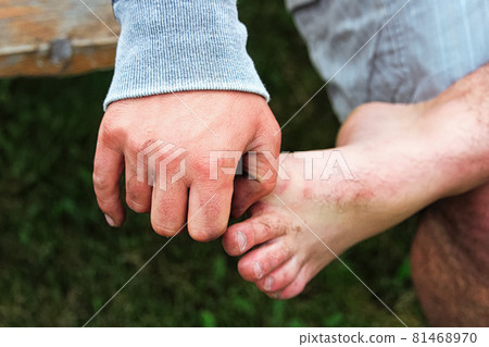 A hand holding onto a bare foot while sitting 81468970