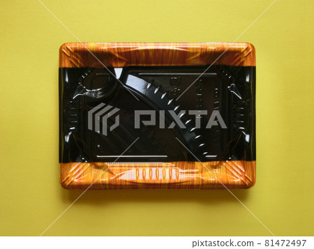 Empty plastic super lunch box placed in the center of yellow paper 81472497