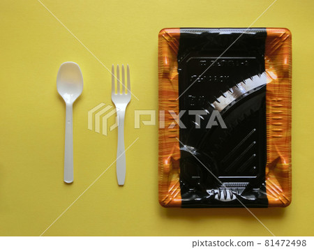 Empty plastic super lunch box, spoon and fork placed on yellow paper 81472498