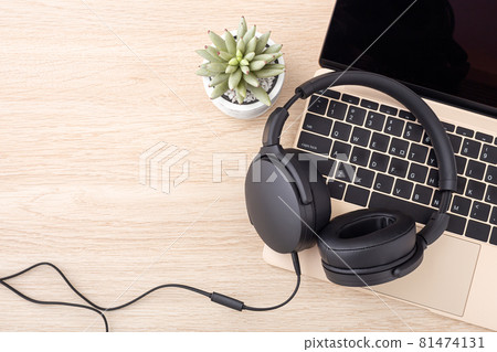 Headphone on laptop on wooden desk 81474131
