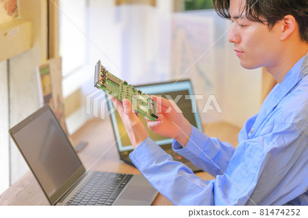 Electrical engineer holding the board with both hands and checking 81474252