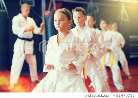 Kids in kimonos practicing karate techniques in group workout at training room Kids in kimonos practicing karate techniques in group workout at training room 81476755