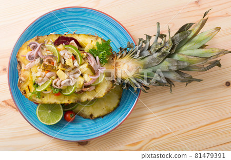 Top view of salad with squid, pineapple on wooden background Top view of salad with squid, pineapple on wooden background 81479391