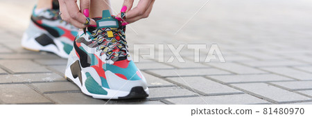 Woman tying shoelaces on sports sneakers closeup 81480970