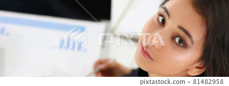 Portrait of young brunette woman with documents on table 81482958