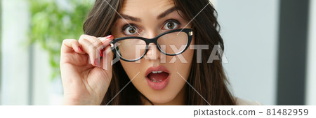 Young surprised woman adjusting glasses for vision 81482959