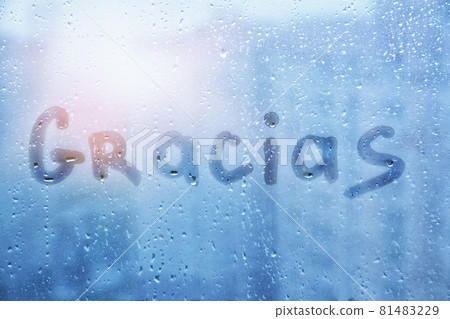 spanish word Gracias are painted on wet blue glass of window on sunset spanish word Gracias are painted on wet blue glass of window on sunset 81483229