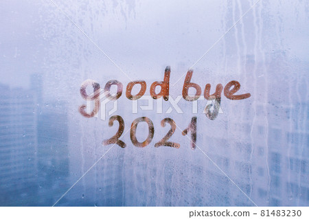 lettering good bye and numbers 2021 paint with finger with streaks of water on splashed by rain foggy glass on blue window 81483230