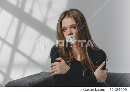 Portrait of a young beautiful sad girl, whose mouth is sealed with a hashtag. 81484609