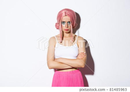 Portrait of angry cute girl with pink wig and glamour makeup, cross arms on chest and sulking mad at someone, feeling offended, standing over white background Portrait of angry cute girl with pink wig and glamour makeup, cross arms on chest and sulking mad at someone, feeling offended, standing over white background 81485963