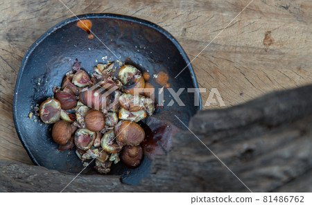 The remaining chestnuts in black ceramic plate on old rustic wooden background. The remaining chestnuts in black ceramic plate on old rustic wooden background. 81486762