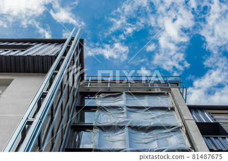 Facade of a new modern building exterior under construction urban house on a blue sky background Facade of a new modern building exterior under construction urban house on a blue sky background 81487675