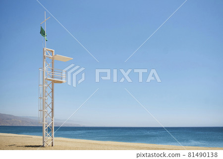 aid station on a beach with calm sea on sunny day and green flag 81490138