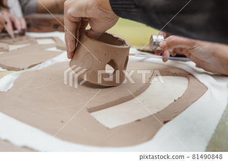 Women's hands knead clay, drawing elements of the product. Production of ceramic products at the master class on ceramics. 81490848