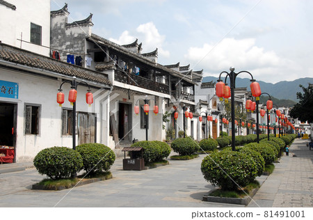 Jiangwan in Wuyuan County, Jiangxi Province, China. Jiangwan is an ancient town in Wuyuan County known for its Tang Dynasty architecture. Wide street with red lanterns and green bushes. 81491001