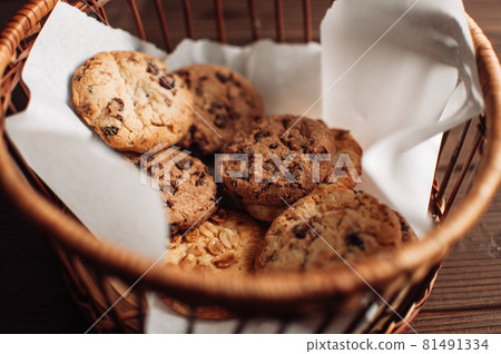 Cookies with chocolate lies in a wicker basket. A basket with gluten free cookies on a wooden table. Selective focus. 81491334