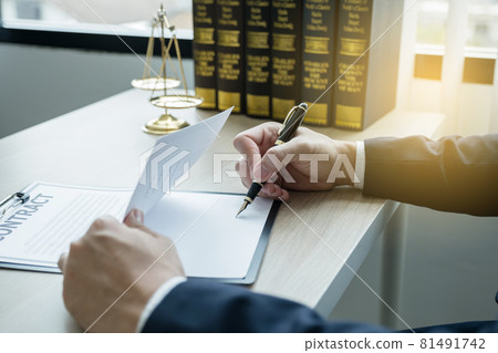 Lawyer hand holding pen and providing legal consult business dispute service at the office with justice scale and gavel hammer 81491742