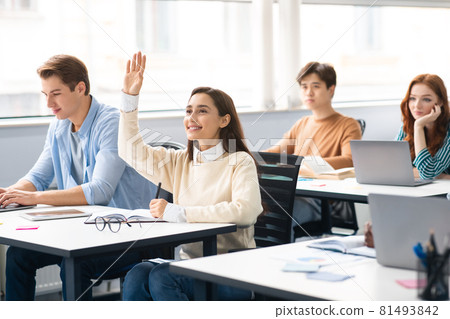 Portrait of female student raising hand at classroom 81493842