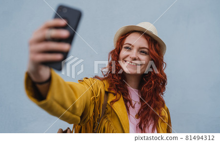 Young woman tourist outdoors against white background on trip in town, taking selfie. Young woman tourist outdoors against white background on trip in town, taking selfie. 81494312