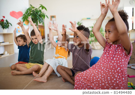 Group of small nursery school children sitting on floor indoors in classroom, playing. Group of small nursery school children sitting on floor indoors in classroom, playing. 81494480