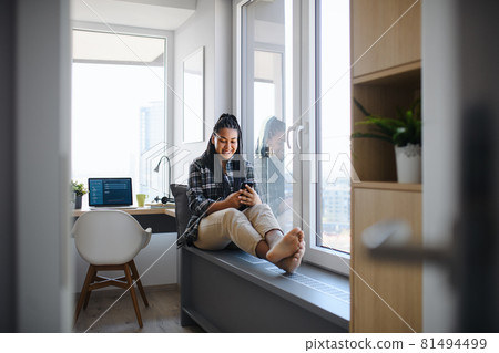 Portrait of happy teenage girl student sitting indoors in bedroom at home, using smarpthone. 81494499