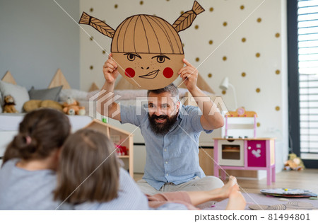 Father with three daughters indoors at home, playing on floor. 81494801
