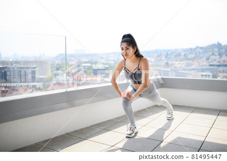 Portrait of young sport woman doing exercise on balcony outdoors in city, stretching. Portrait of young sport woman doing exercise on balcony outdoors in city, stretching. 81495447